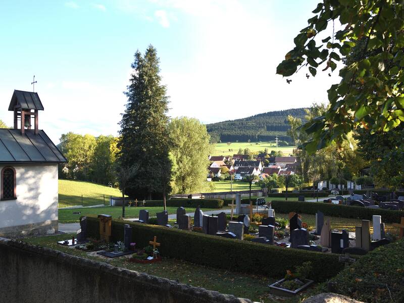 Bild vom Teil des Friedhofs mit einem weiten Ausblick, Gräbern und der Kapelle