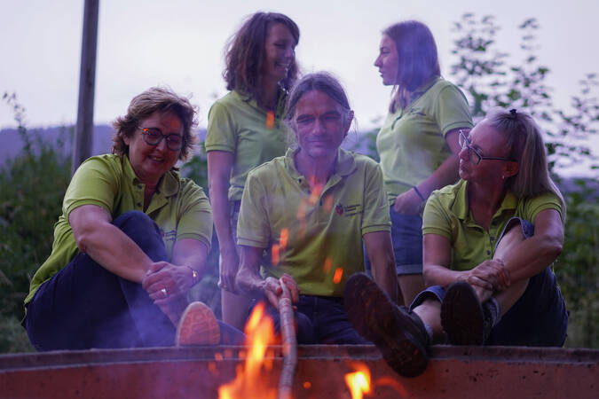 Fünf Personen des Schwäbischen Albvereins welche hinter einem Lagerfeuer sitzen und sich teilweise unterhalten