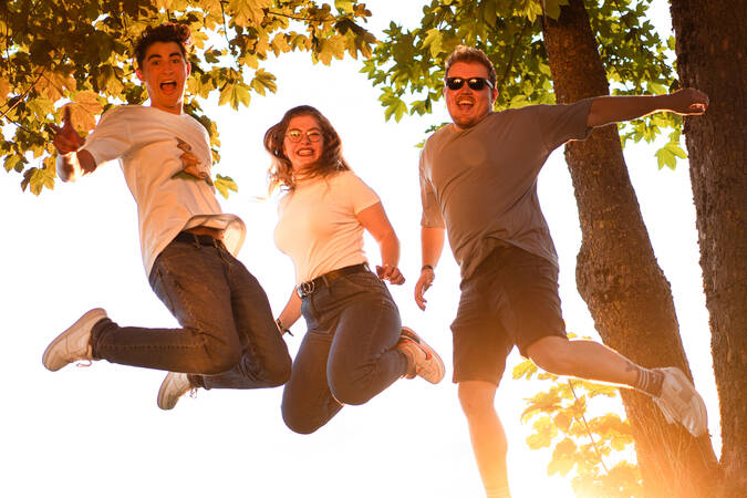 Bild von drei Jugendlichen der Jugendgruppe welche in vor Bäumen in die Luft springen