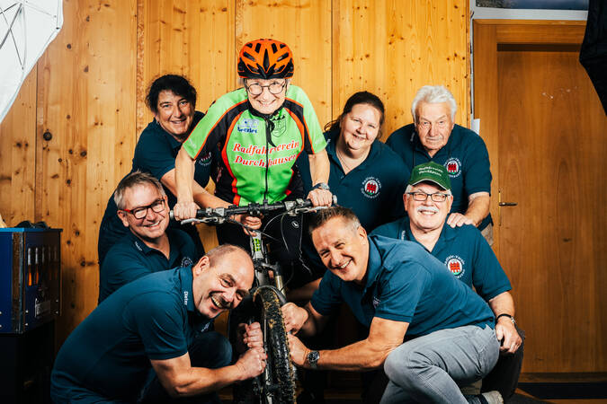 Bild von acht Personen Personen des Radsportvereins in der Mitte aller Personen ist ein Mann auf dem Fahrrad