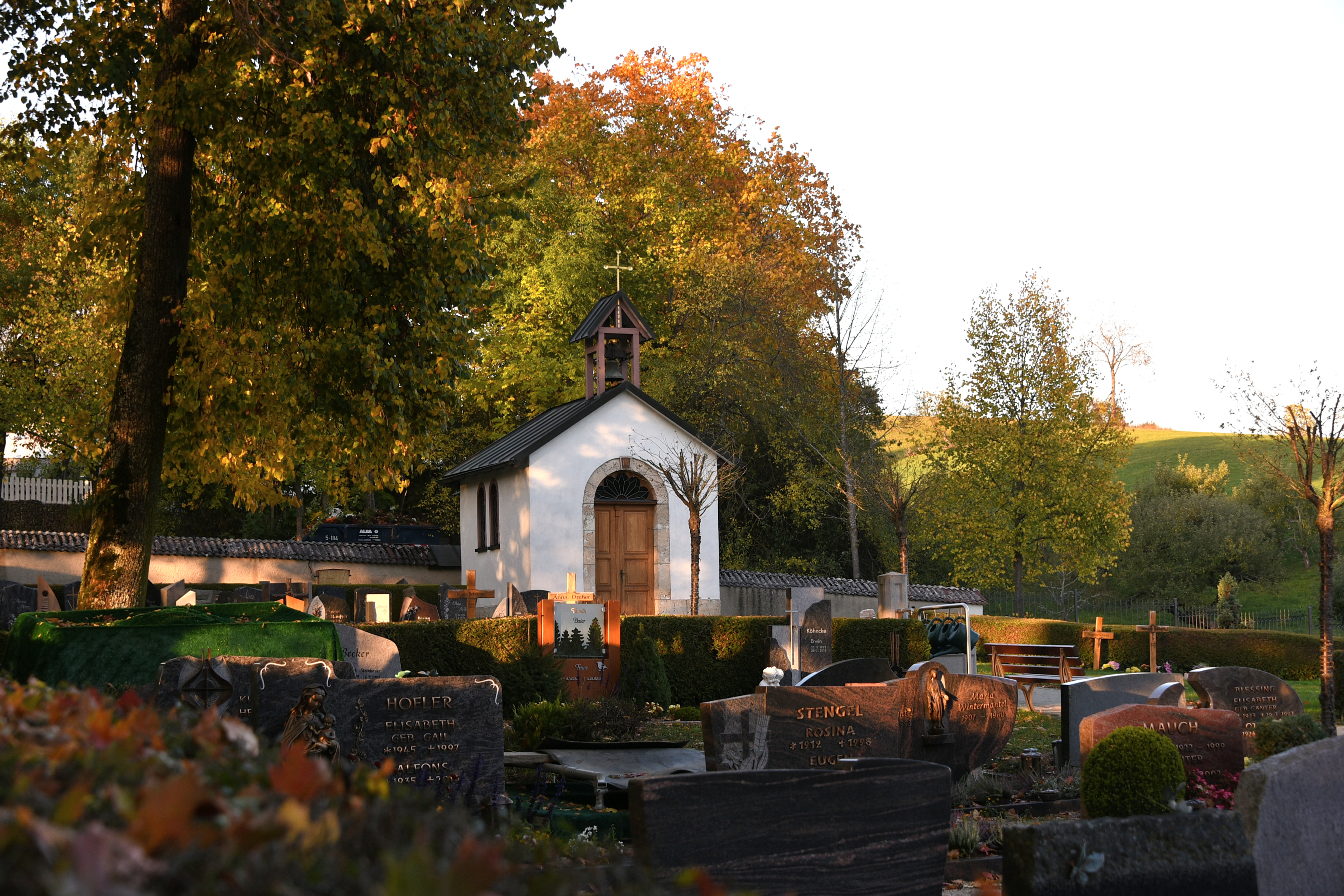 Bild vom Teil des Friedhofs mit Gräbern im Vordergrund und der Kapelle im Hintergrund